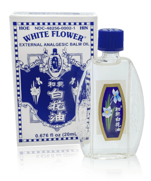 Clear fancy oval-shaped bottle of Minyak Angin White Flower Embrocation containing 0.676 fluid ounces (20 milliliters) of external analgesic balm. Chinese and english text.