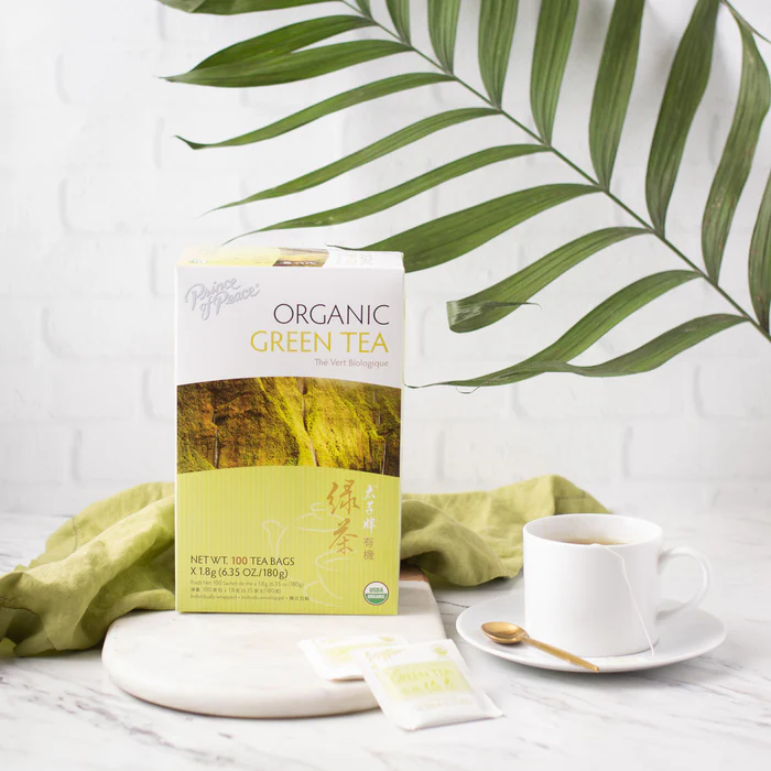 Image of the box and a cup of Prince of Peace Organic Green tea in aesthetic background