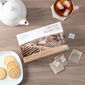 image of box and a brewed cup of Prince of Peace Pu-Erh tea with assorted items in the background